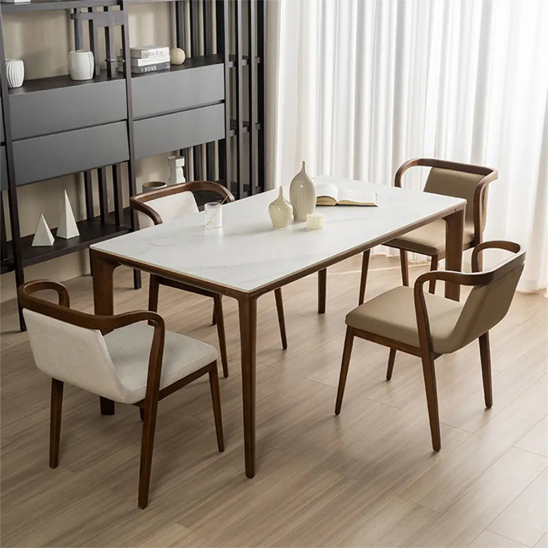 A contemporary dining room with a marble table and wooden Mid-Century Modern chairs with cushioned seats and backs, set against a backdrop of sheer curtains and minimalist decor.