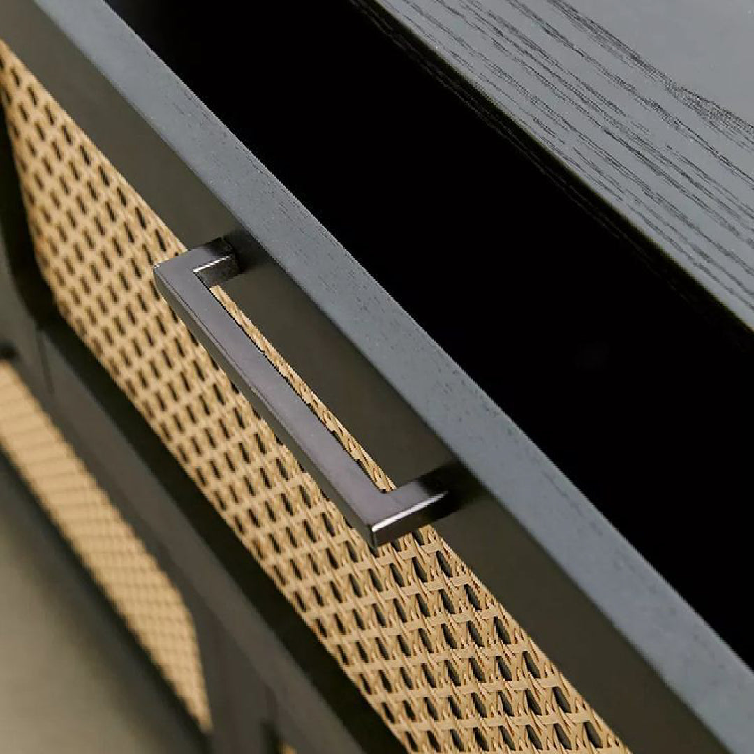 Close-up of a black rattan chest-of-drawers handle, showcasing its sleek, modern design with intricate woven detailing.