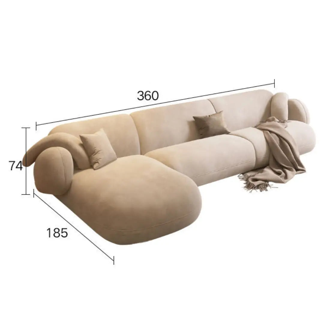Beige L-shaped sofa with a modern, minimalist design, featuring a rounded chaise lounge on the left, plush cushions, and a cozy throw draped over the armrest. Dimensions are labeled as 360 cm in length, 185 cm in depth, and 74 cm in height
