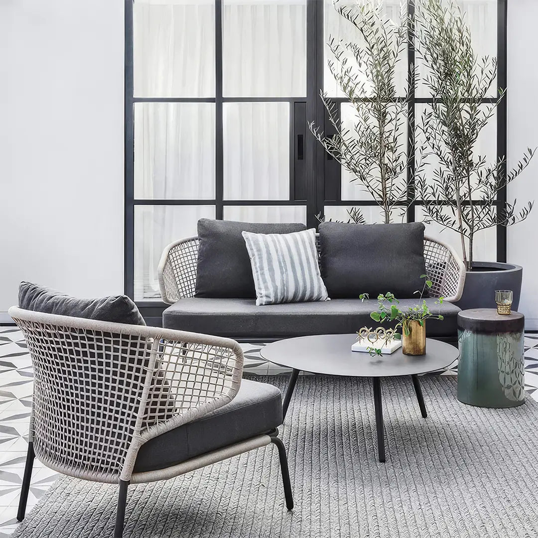 Modern rope outdoor sofa set with waterproof cushions in a stylish patio setting, featuring a sleek black metal frame and contemporary round coffee table – perfect for Brightly Home summer gardens.