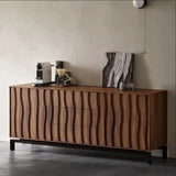 The surface of the sideboard is decorated with various items, including a coffee machine, a pour-over coffee setup, a small piece of art, and a decorative jar, showcasing its versatility in use. The sideboard stands on sturdy black metal legs, which contrast nicely with the warm tones of the walnut wood. The background is a plain light-colored wall, emphasizing the sideboard's sophisticated design and making it the focal point of the space.