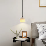 Warm-glow alabaster pendant light hanging beside a bed with a marble side table and indoor bonsai tree, styled in a serene, contemporary bedroom.