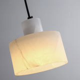Close-up view of an alabaster white marble pendant light, showcasing its natural stone texture and soft warm illumination against a grey background.