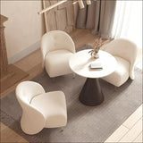 A top-down view of three Alpine Shearling Armless Chairs surrounding a round black and gold table in a minimalist living room, creating a warm and inviting atmosphere.