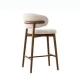 The stool features a cushioned seat and a curved backrest, both upholstered in a light, textured fabric for added comfort. The frame and legs are made of wood, providing a sturdy and natural appearance. The backrest is supported by a horizontal wooden beam that wraps around the back, enhancing the modern aesthetic.