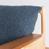 Close-up of a blue textured cushion on a wooden chair with a white background