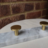 Brass cabinet knobs on a marble surface with a brick wall background
