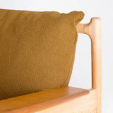 Brown textured cushion on a wooden chair with a light gray background