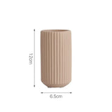 A delicate pink vertical ribbed vase, measuring 12 cm in height and 6.5 cm in diameter, ideal for adding a touch of elegance to small spaces with its slim and tall design.