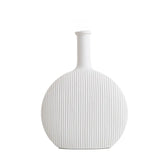 A minimalist white ceramic vase with a ribbed texture, featuring a broad round body and a narrow neck, against a clean, neutral background.