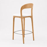 Close-up of mid-century bar stool with curved oak wood backrest and white upholstered seat