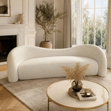 Contemporary Gilla Sofa in cream white upholstery, styled as a statement sofa in a modern living room with large windows, soft neutral tones, and a luxury minimalist coffee table.