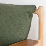 Green textured fabric draped over a wooden chair armrest.