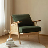 Green cushioned chair with wooden frame in a room with books and a plant.