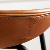 Close-up view of a Hackney Industrial Leather Bar Stool showcasing the fine craftsmanship of the saddle-brown leather upholstery, accentuated with detailed stitching and supported by a sleek black metal frame.