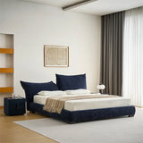 Luxurious navy blue upholstered bed with plush headboard and footboard in a chic bedroom with herringbone flooring