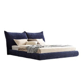 Luxurious navy blue upholstered bed frame with plush headboard and neutral bedding, set in a serene bedroom with minimalist decor.