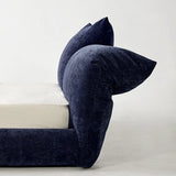 Side view of a navy blue upholstered bed headboard with matching pillows, showcasing its plush texture and modern design