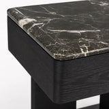 Angled close-up of the Maidstone marble bedside table featuring rounded edges and a sculptural black wood base