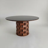 Round table with woven wooden base on a plain background