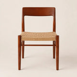 Front view of a mid-century dining chair with walnut-toned wood frame and woven rattan seat in a studio setting.