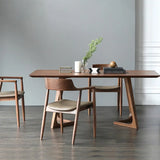 dining setup featuring a mid-century modern dining table and chairs. The table has a sleek rectangular wooden top and unique angled legs that form an open triangular shape, providing a contemporary look.