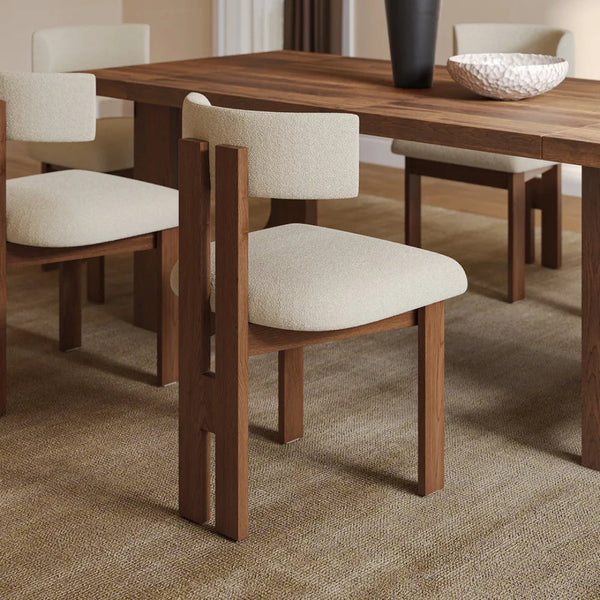 Mid-century Sunbury Bouclé Dining Chairs with walnut wood frames paired with a matching dining table in a cozy, neutral-toned dining space, highlighting their sleek and timeless design.