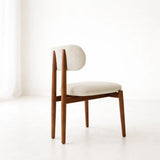 Mid-century wooden dining chair with upholstered seat and curved backrest in a neutral UK dining room setting