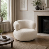 Modern white accent chair styled in a bright living room with side table, fireplace and neutral interior decor.