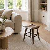 Modern wooden short stool placed beside a fireplace in a neutral UK living room with classic wall detailing and soft textures.