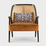 Front view of the Qeinn Medieval Rattan Armchair featuring a natural rattan backrest, dark wooden frame, and plush mustard-colored velvet seat cushion, with a decorative geometric patterned pillow for added style and comfort.