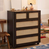 Qienn Rattan five-drawer chest in black, displayed in a contemporary bedroom setting, highlighting its modern yet rustic design with rattan drawer fronts.