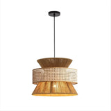 The image displays a stylish pendant light with a distinctive three-tier design. The top and bottom tiers are crafted from a textured wood material, while the middle tier is made of a perforated golden rattan, allowing for a warm, ambient light to filter through. The light hangs from a simple black rod, complementing the natural aesthetic of the lamp. This design is perfect for adding a touch of organic elegance to any room, enhancing the décor with both its light and its artful construction.