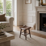 Dark wood short stool styled in an open-plan UK home with neutral sofa, soft rug and warm modern interior details.