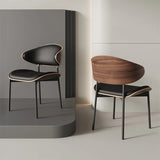 Modern dining room showcasing two Silhouette Leather Dining Chairs in black with walnut wood accents, positioned elegantly against a minimalist gray backdrop.