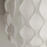 Close-up of a modern white wave-patterned wall feature made of curved panels, showcasing a smooth and flowing design that creates a textured and dynamic visual effect.