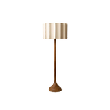 Minimalist floor lamp featuring a sleek walnut base that tapers towards a stable, rounded foot, topped with an elegant cream pleated lampshade, presented against a clean white background for a modern look.