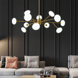 Modern Tadley 12-lights globe hardwired chandelier illuminating a chic living room with black vertical panels, featuring plush gray sectional sofas and a minimalist coffee table.