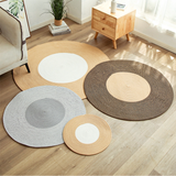 A collection of round, hand-tufted rugs in various sizes displayed on a wooden floor. The rugs come in neutral shades of beige, gray, and brown, each featuring a concentric circle pattern that adds a dynamic and organic feel to the room's decor. The placement suggests versatility in use for different areas within a home.