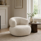 White boucle armchair in a modern living room with fireplace, neutral rug and soft contemporary styling.