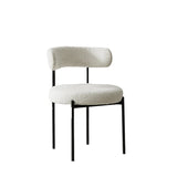 White boucle fabric dining chair with a minimalist black metal frame and a rounded backrest, perfect for modern interiors with a touch of contemporary design.